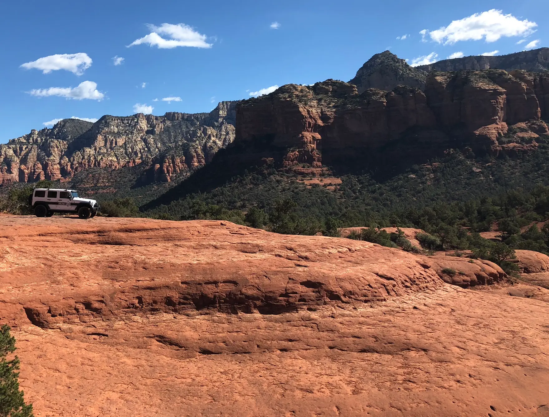 A Jeep on red slickrock with the Sedona cliffs rising behind — the Off-Road Immersion leadership offsite in Arizona.